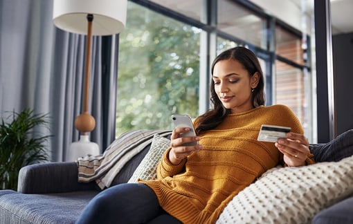 woman at home shopping online on her mobile device woman at home shopping on her mobile device holding credit card