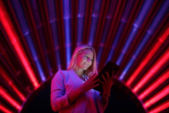 Woman on tablet in dark room with red lights